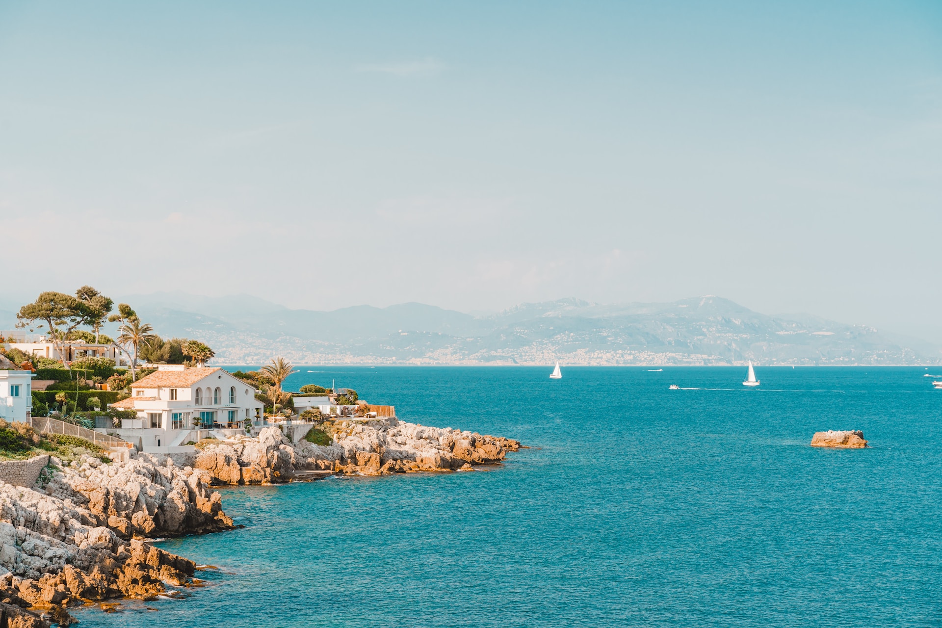 Houses on rocky shoreline above blue water along coast of Antibes