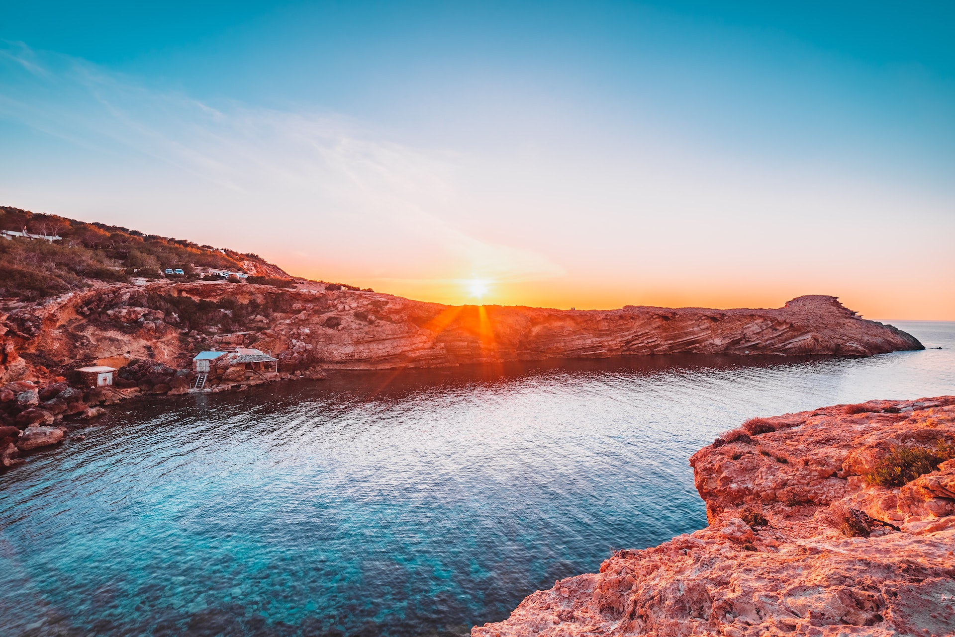Ibiza cove with red rocky coast at sunset